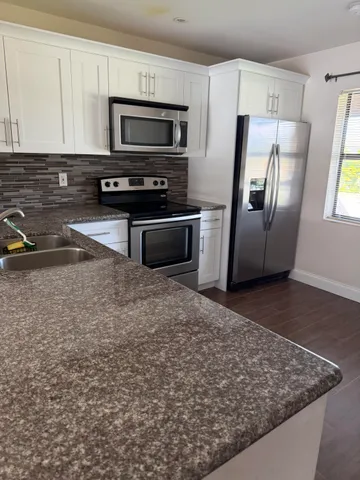 a kitchen with stainless steel appliances granite countertop a refrigerator a stove a sink and a microwave