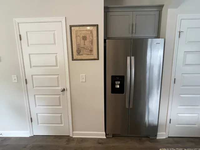 a view of a refrigerator in kitchen and an empty room with wooden floor windows