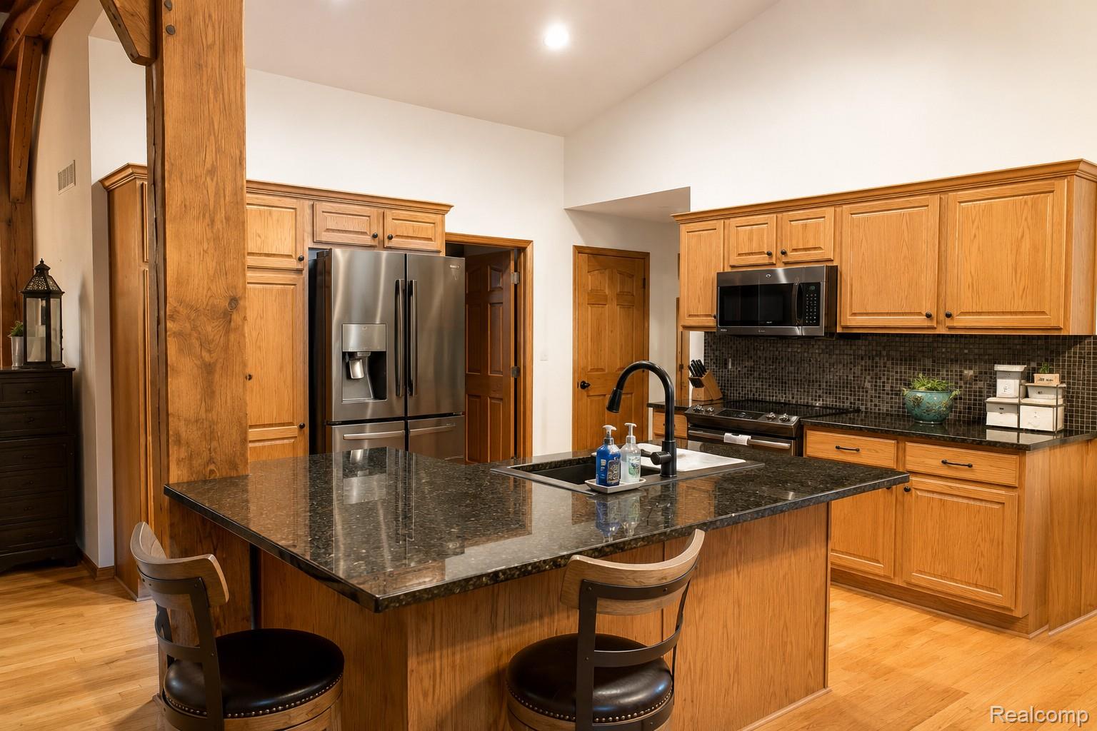 7542 Newberry Road Durand, MI 48429 - Photo 10 of 25 Kitchen featuring wood cabinetry, appliances, dark stone countertops, and a central island with an integrated sink