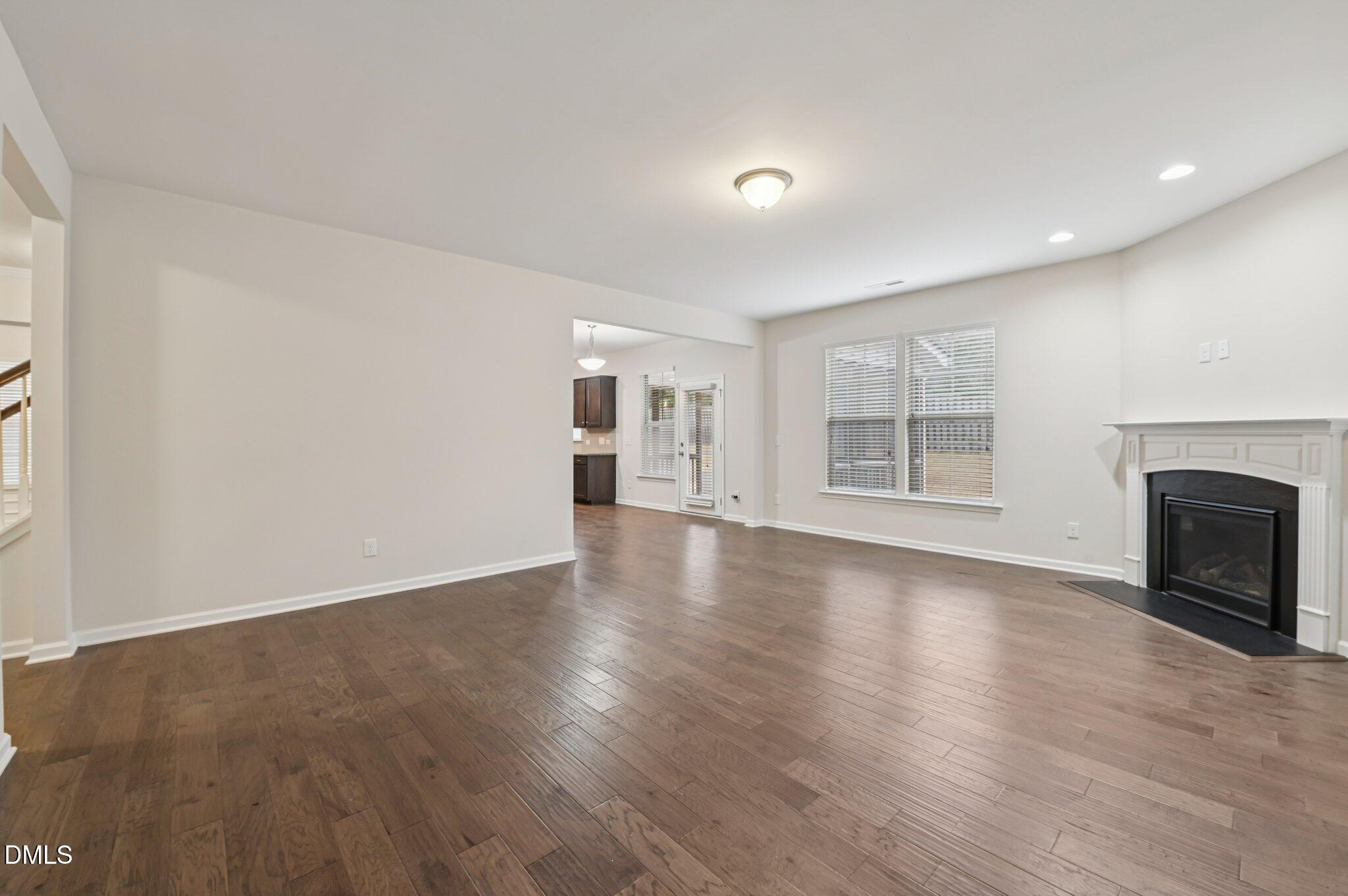 1024 Laredo Lane Durham, NC 27703 - Photo 6 of 32 an empty room with wooden floor fireplace and windows