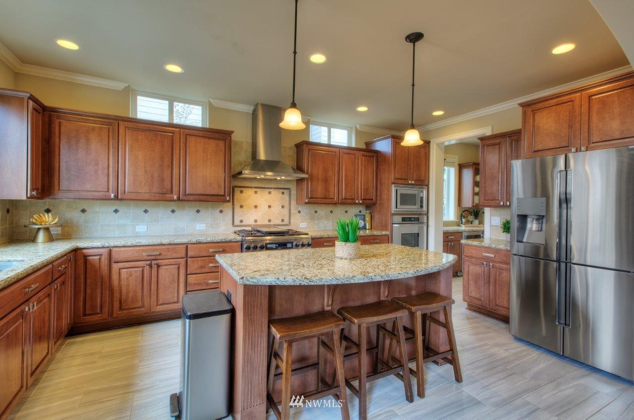 123 Ilwaco Place Southeast Renton, WA 98059 - Photo 9 of 33 a kitchen with kitchen island granite countertop wooden floor cabinets and refrigerator