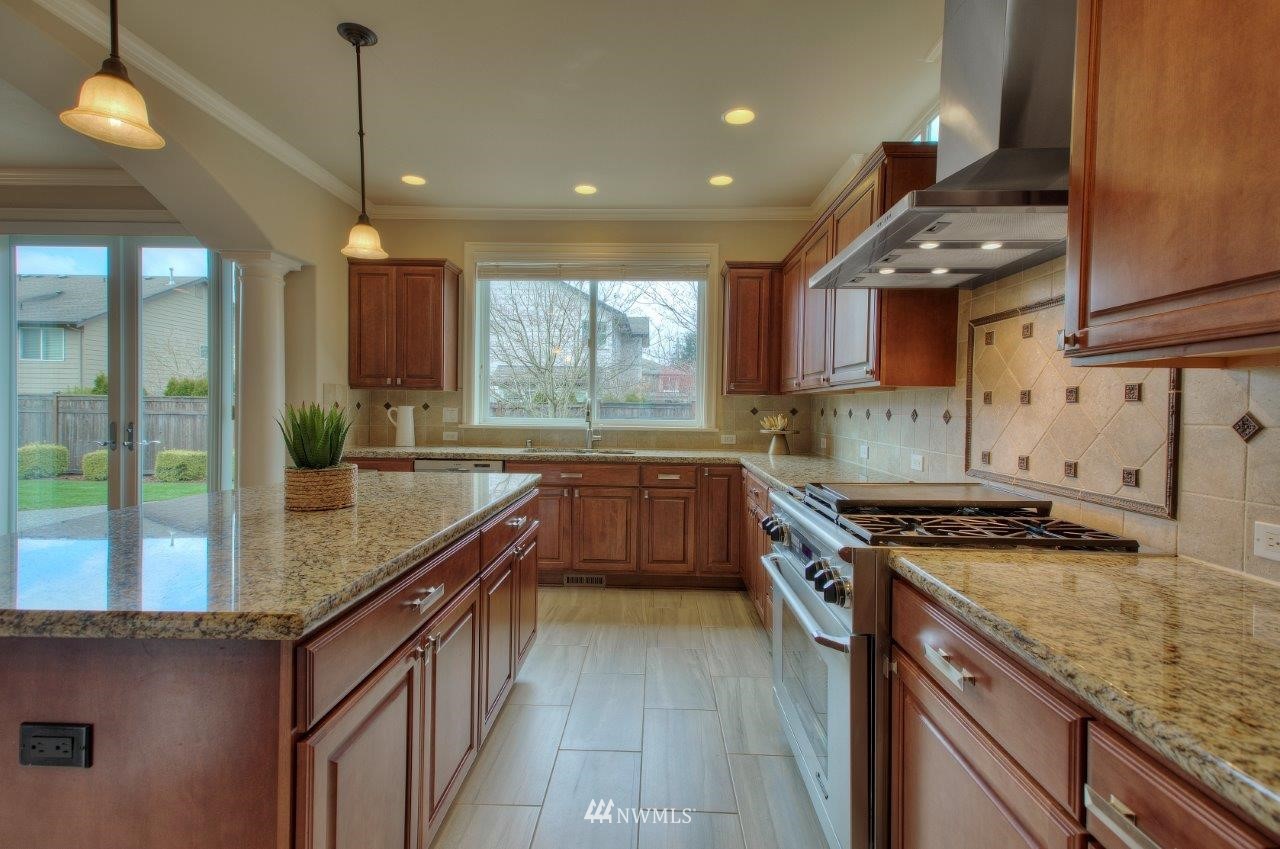 123 Ilwaco Place Southeast Renton, WA 98059 - Photo 10 of 33 a kitchen with kitchen island granite countertop a sink a counter top space appliances and cabinets