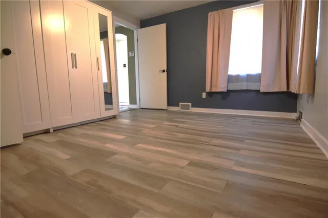 a view of an empty room with closet and wooden floor