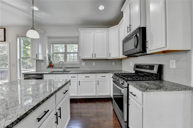 a kitchen with stainless steel appliances granite countertop a stove top oven a refrigerator a sink and dishwasher with wooden floor