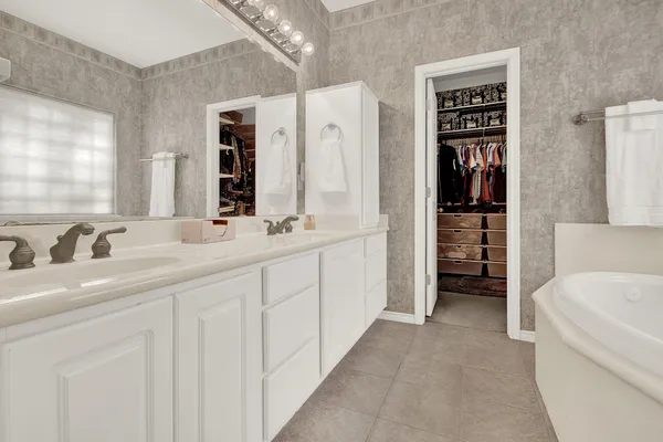 a spacious bathroom with a double vanity sink a mirror and a bathtub