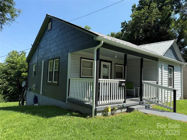 a view of a house with a yard and a large tree