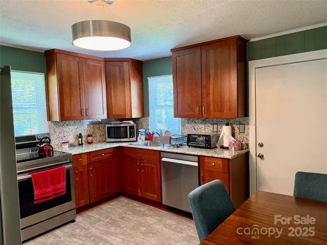 a kitchen with stainless steel appliances granite countertop a sink dishwasher stove and cabinets with wooden floor
