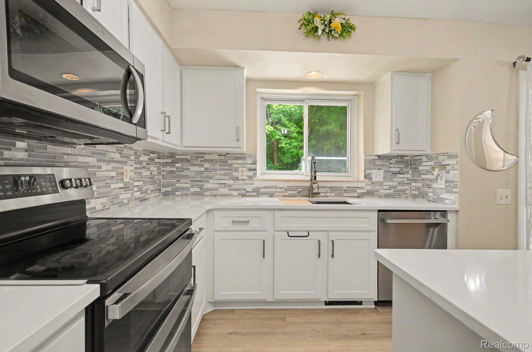 425 Thornridge Court Rochester, MI 48307 - Photo 6 of 35 Modern kitchen featuring white cabinetry, light-colored countertops, and a mosaic tile backsplash