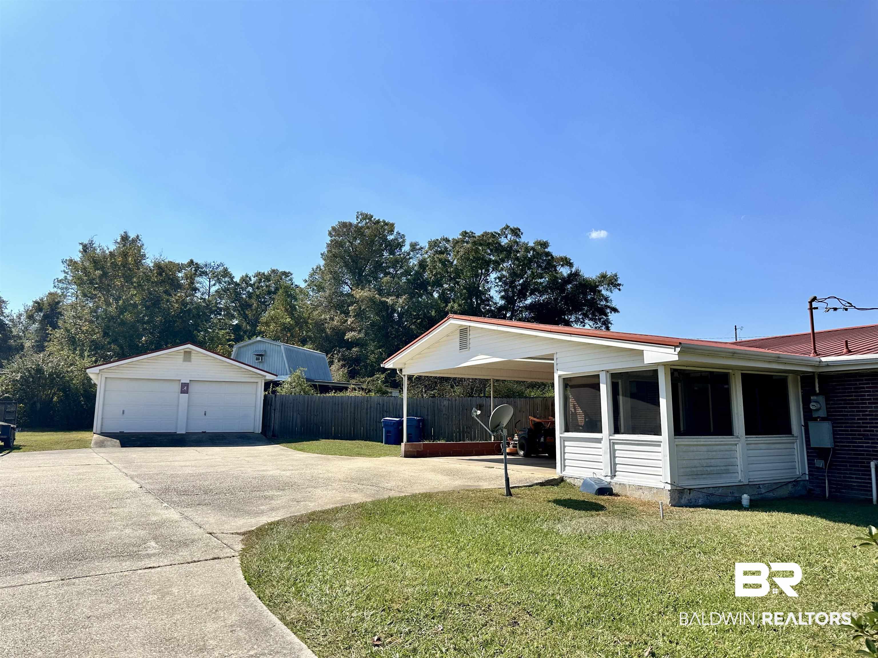 2593 Foshee Road Brewton, AL 36426 - Photo 11 of 15 View of front of property with a sunroom, an outdoor structure, a front lawn, and a garage