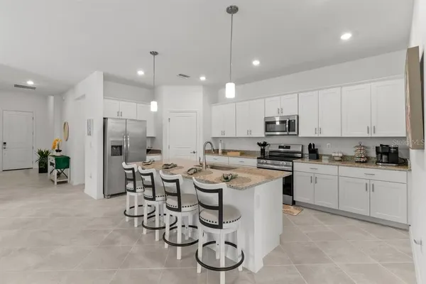 a room with stainless steel appliances kitchen island granite countertop a sink and cabinets