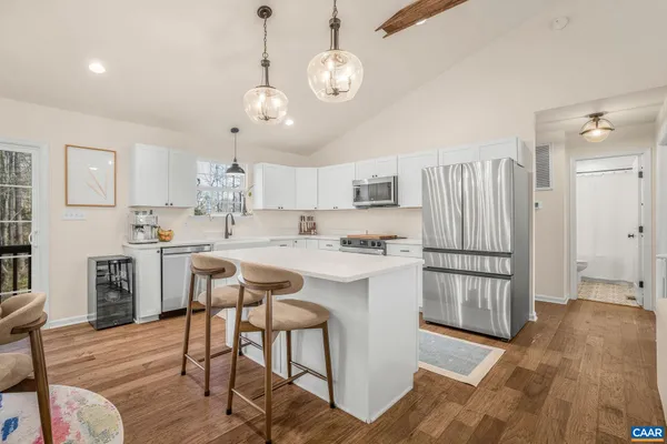 a kitchen with stainless steel appliances granite countertop a refrigerator a sink dishwasher a stove and white countertops with wooden floor