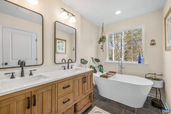 a bathroom with double vanity sinks a large mirror and a bathtub