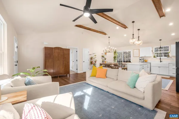 a living room with furniture kitchen view and a chandelier