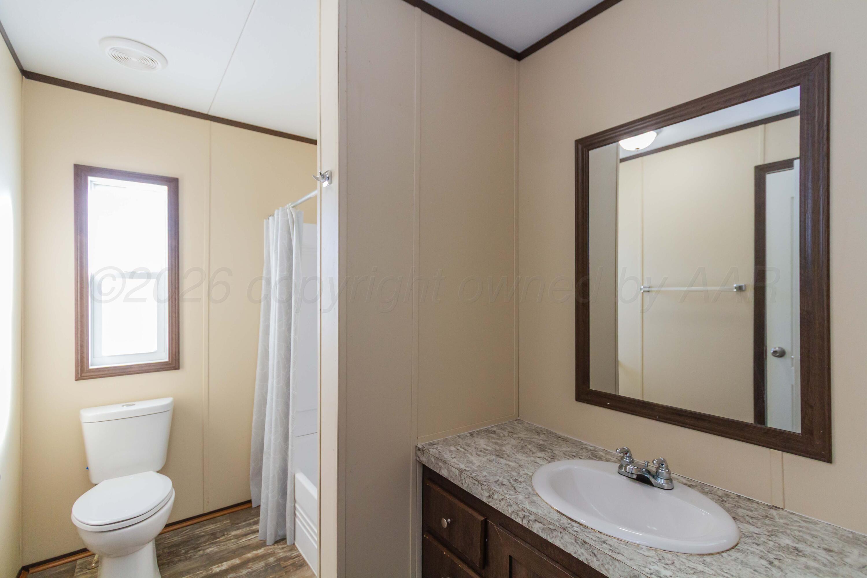 108 North Canadian Street Wheeler, TX 79096 - Photo 32 of 42 a bathroom with a granite countertop sink toilet and a mirror