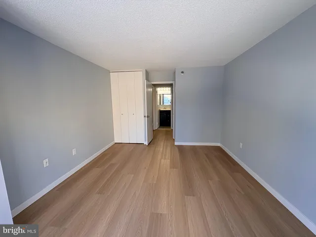 a view of an empty room with wooden floor and window