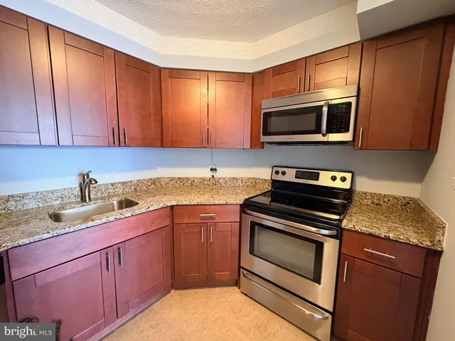a kitchen with granite countertop cabinets stainless steel appliances and a sink