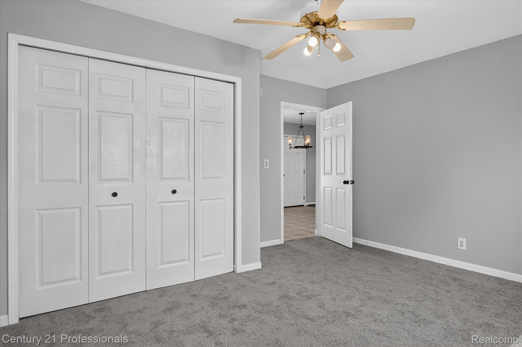 648 Newport Road Carleton, MI 48117 - Photo 17 of 37 Expansive bi-fold closet doors with black hardware, complementing the light gray walls and gray carpet flooring