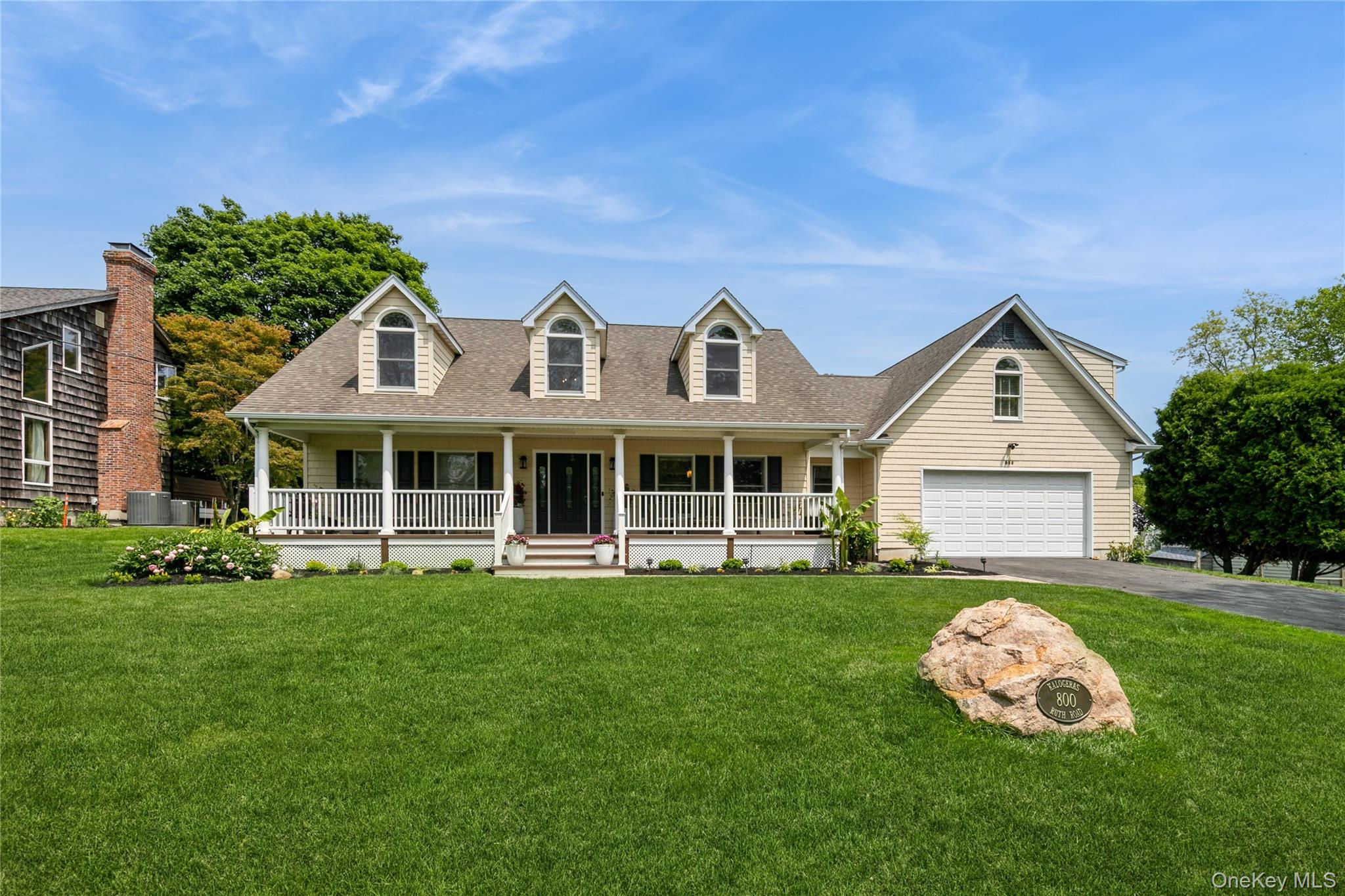 a front view of a house with a garden and trees
