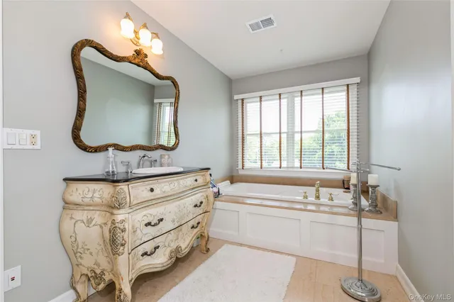 a bathroom with a double vanity sink mirror and bathtub