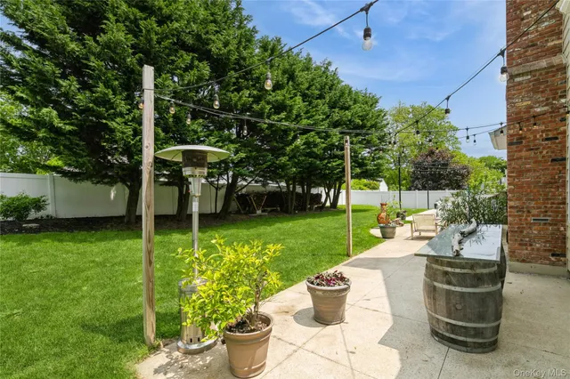 a view of a patio with table and chairs potted plants and a large tree