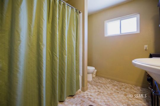 2030 South Inyo Street Ridgecrest, CA 93555 - Photo 33 of 42 a bathroom with a sink a toilet and shower curtain