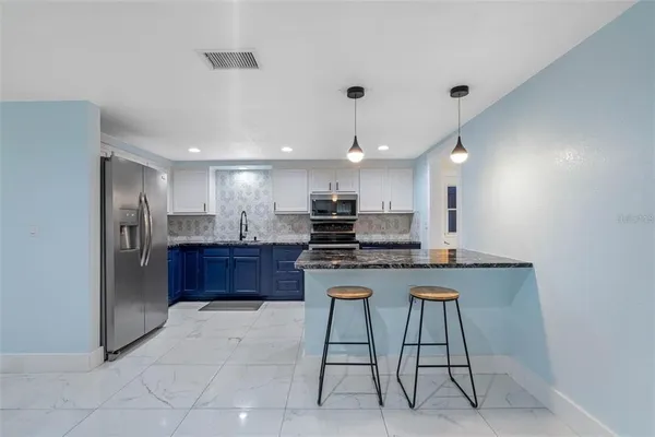 a kitchen with stainless steel appliances kitchen island granite countertop a refrigerator and a stove top oven