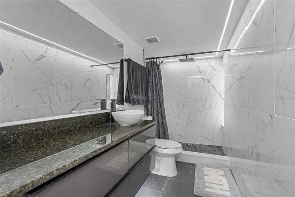 a bathroom with a granite countertop bathtub shower sink and toilet