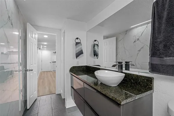 a bathroom with a granite countertop sink a mirror a vanity and a shower