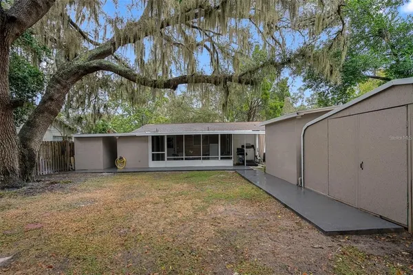 a view of a house with a small yard and a large tree