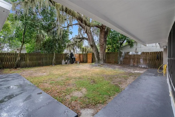 a backyard of a house with a tree and wooden fence