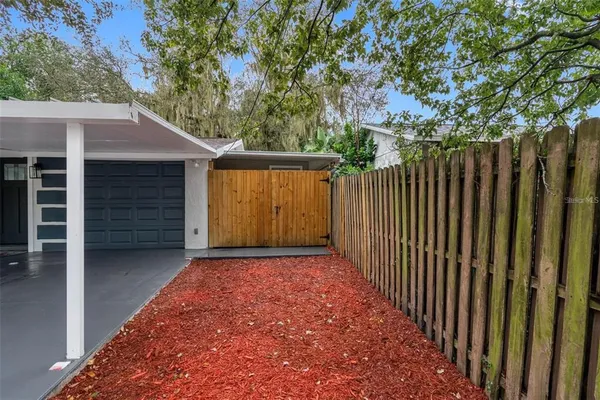 a view of backyard with wooden fence and a large tree