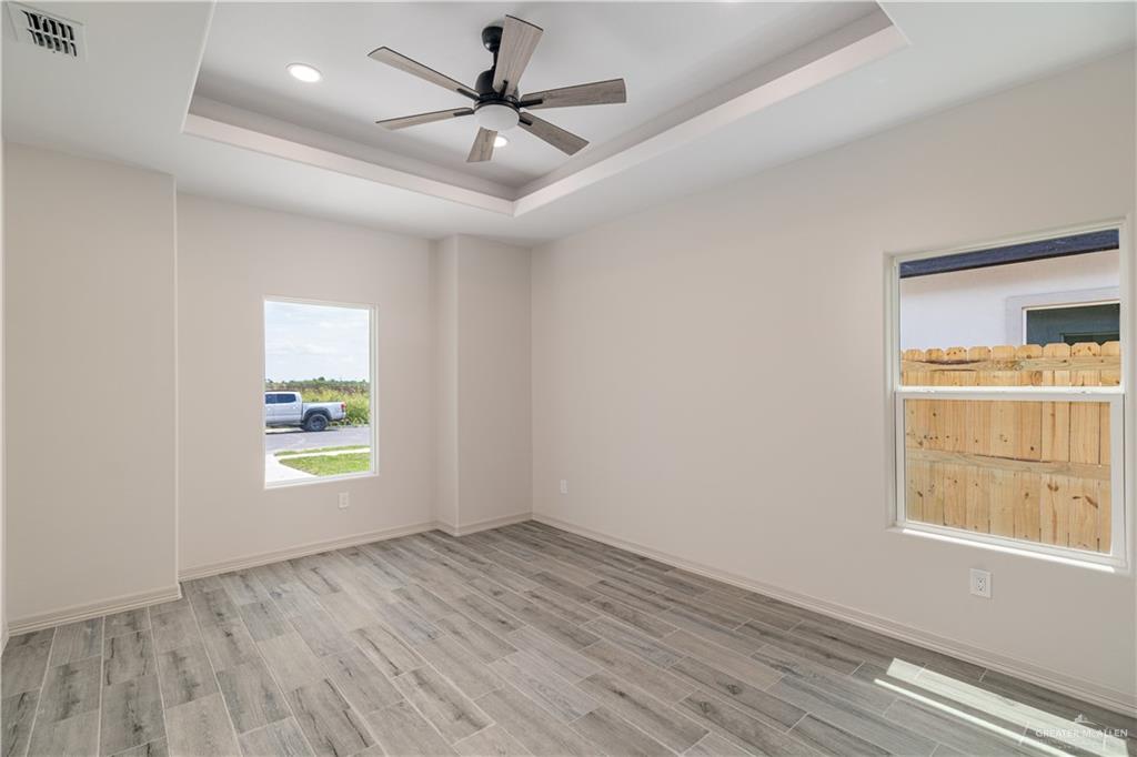 2118 Trinity Street Donna, TX 78537 - Photo 8 of 13 an empty room with wooden floor windows and a ceiling fan