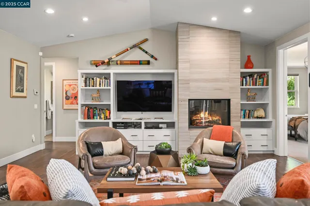 a living room with furniture kitchen view and a wooden floor