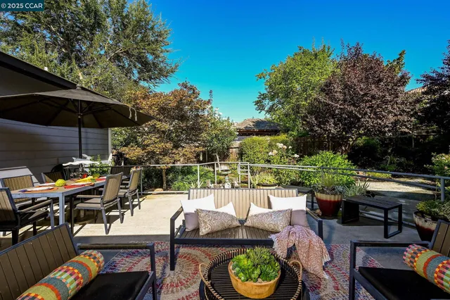 a dining hall with stainless steel appliances kitchen island granite countertop a dining table chairs and a refrigerator