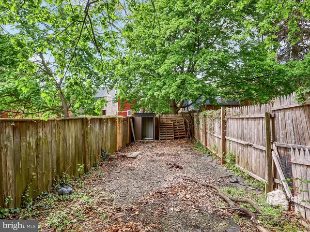 a view of backyard with wooden fence and trees