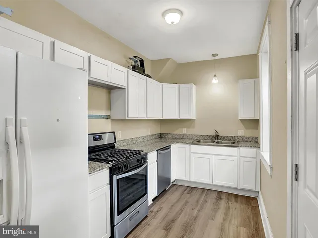 a kitchen with stainless steel appliances a sink cabinets and wooden floor