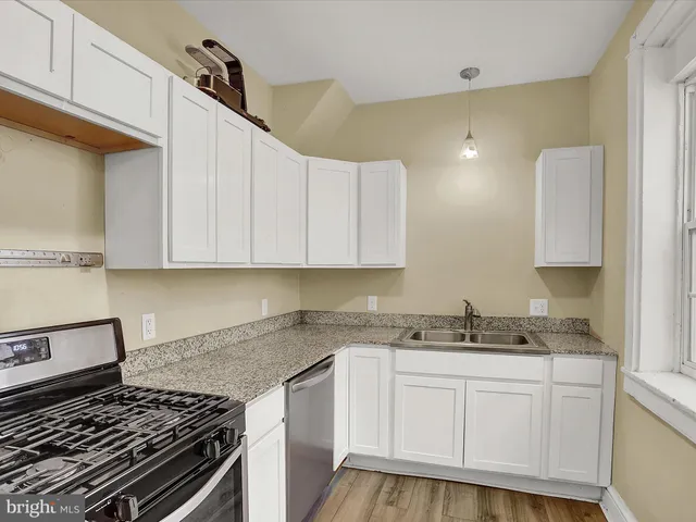 a kitchen with granite countertop a sink a stove and cabinets