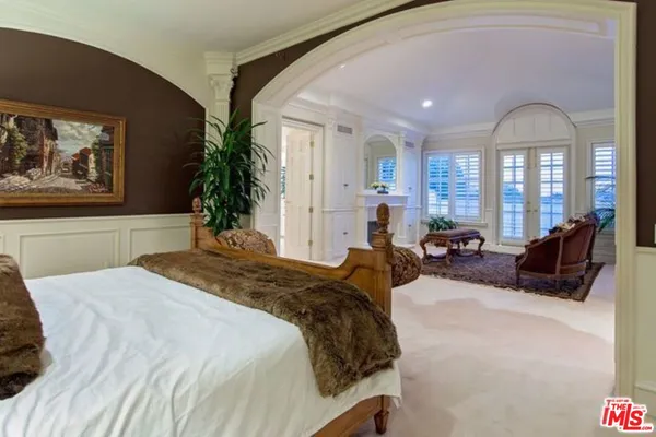 a spacious bedroom with a bed a couch and potted plant on the dresser