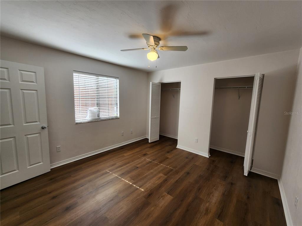 5823 Southwest 9th Place, Unit H55 Gainesville, FL 32607 - Photo 7 of 50 an empty room with wooden floor chandelier fan and windows