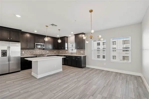 a large kitchen with a large center island wooden cabinets and stainless steel appliances
