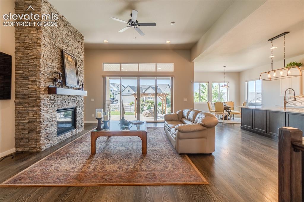 1061 Native Dancer Terrace Colorado Springs, CO 80921 - Photo 5 of 50 Open-concept living space featuring a stacked stone fireplace with a wood mantel, wood-finish flooring, and a ceiling fan