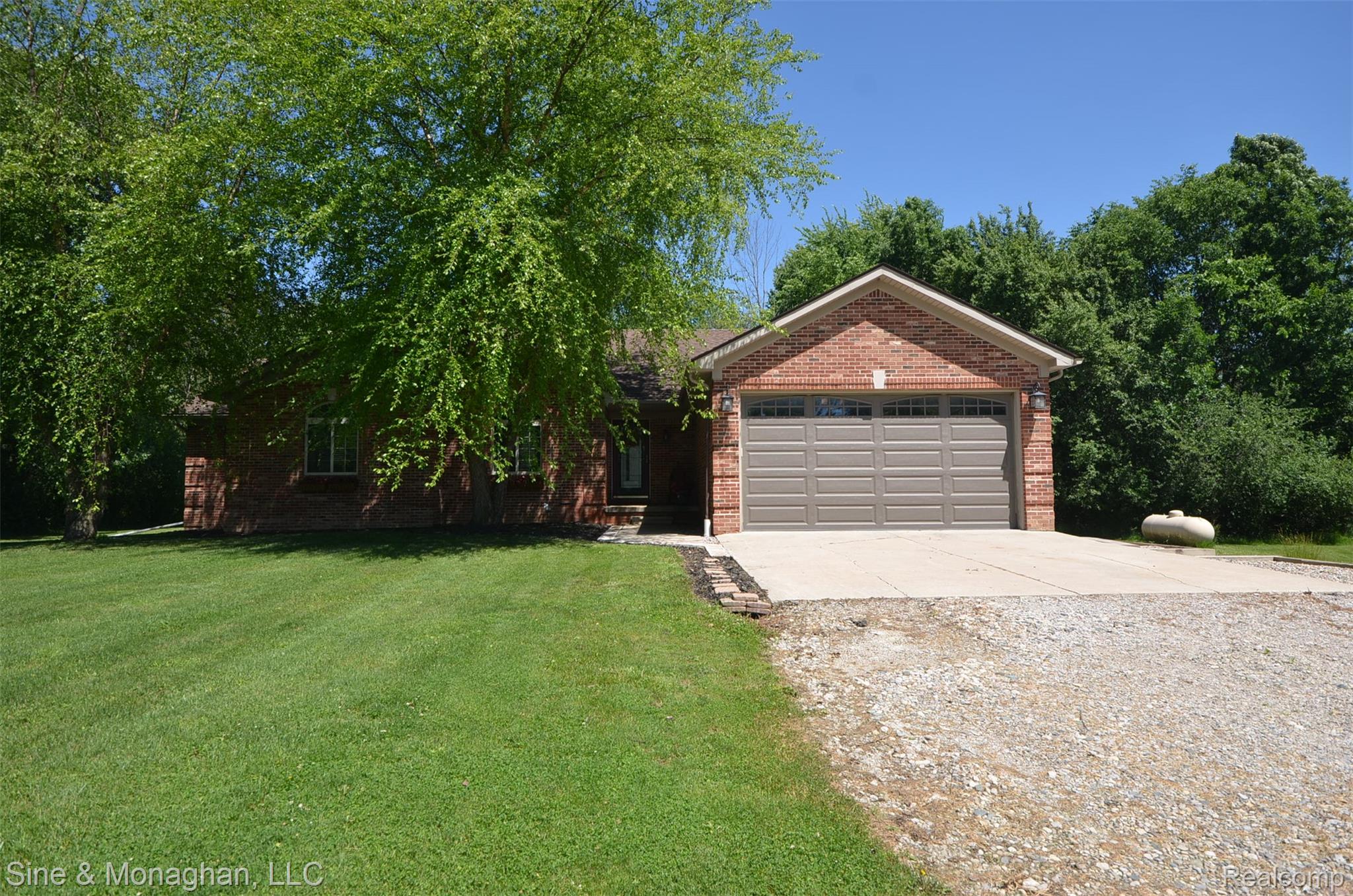 76152 Burman Road Richmond, MI 48062 - Photo 5 of 75 Brick exterior with an attached two-car garage, concrete driveway, and gravel parking area