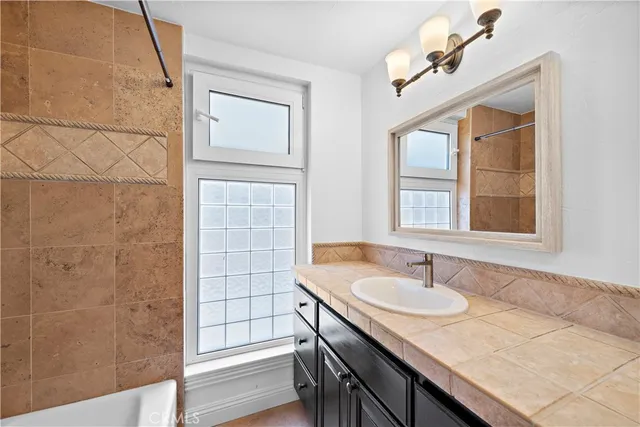 a bathroom with a granite countertop sink a mirror and a shower