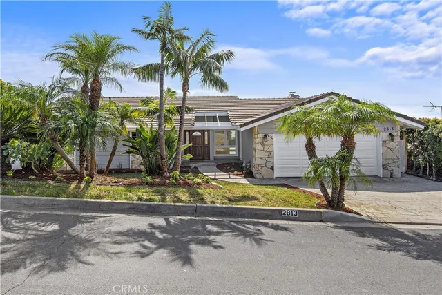 a view of a house with palm trees and a small yard