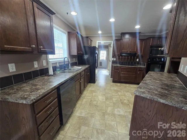 a large kitchen with kitchen island granite countertop a sink and dishwasher a stove top oven with wooden floor