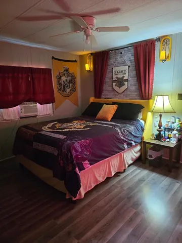 a bedroom with a bed and dresser with wooden floor