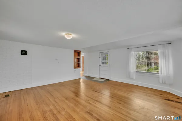 a view of an empty room with wooden floor and a window