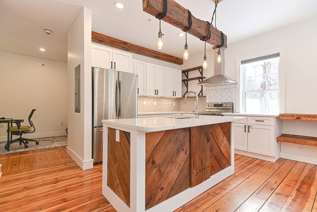 166 Littleton Road, Unit 1 Harvard, MA 01451 - Photo 5 of 23 a kitchen with stainless steel appliances granite countertop a refrigerator a sink dishwasher a stove and white countertops with wooden floor