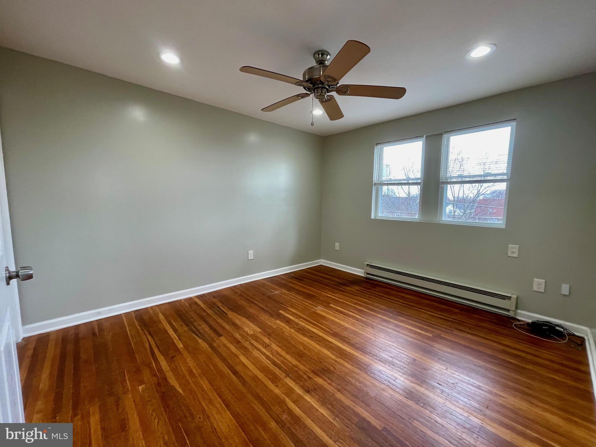 412 East Providence Road Aldan, PA 19018 - Photo 6 of 13 an empty room with wooden floor fan and windows