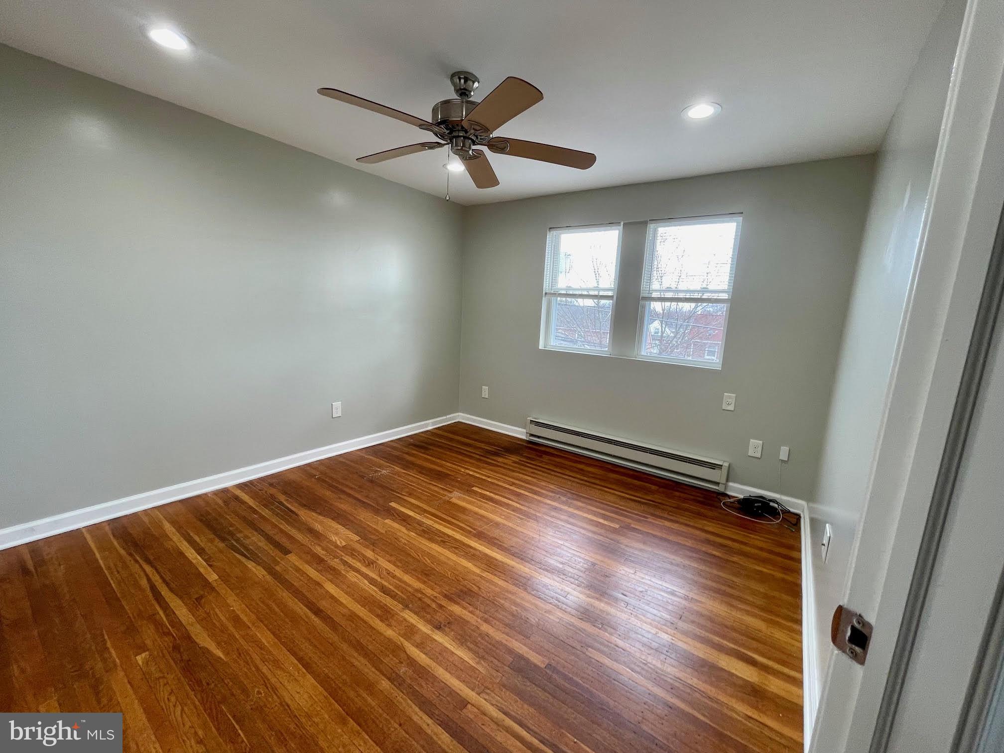412 East Providence Road Aldan, PA 19018 - Photo 7 of 13 an empty room with wooden floor fan and windows